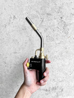 Hand holding a Pyralit torch against a gray concrete background