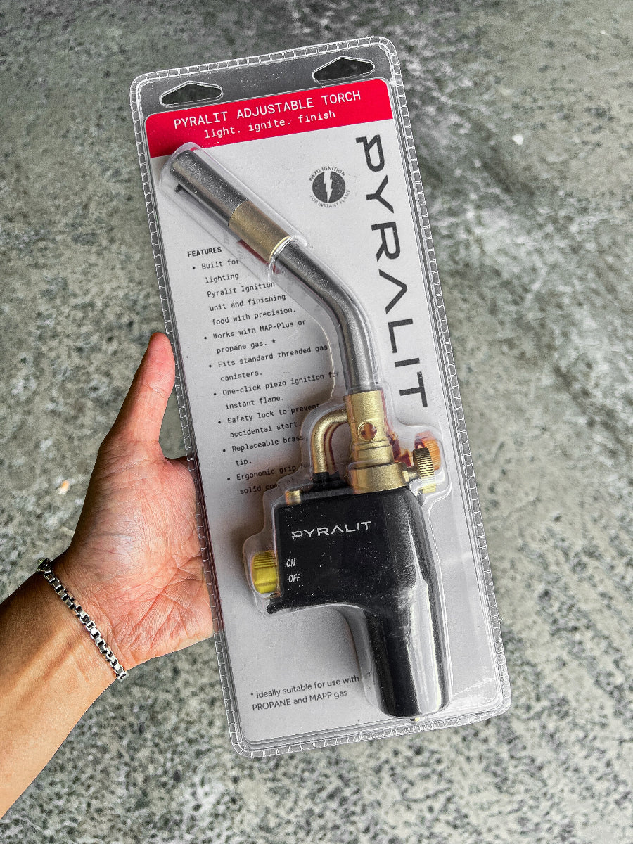 Pyralit adjustable torch held in hand with packaging on a gray surface