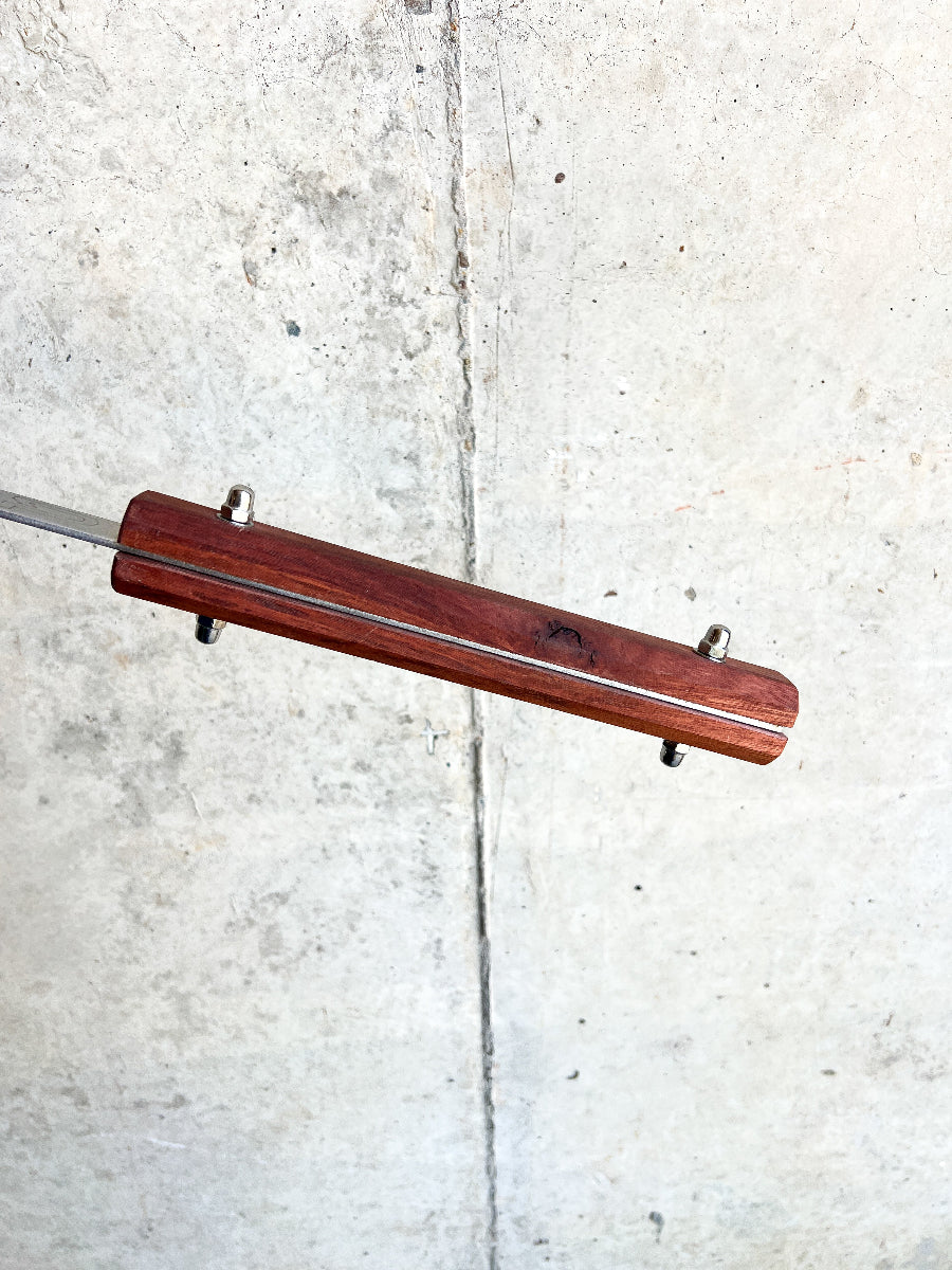 Wooden stick with metal components on a concrete surface